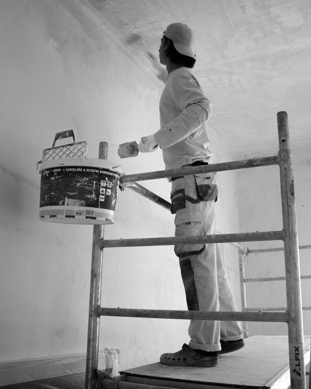 Artisan plâtrier sur un échafaudage, en train de lisser un mur