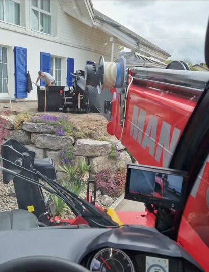 Chantier devant une maison aux volets bleus, vu depuis la cabine du télescopique